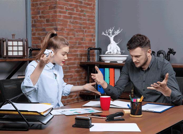 Um homem e uma mulher sentados à mesa discutindo