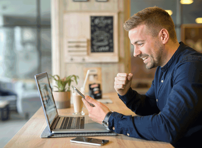 Homem comemorando em frente a um notebook