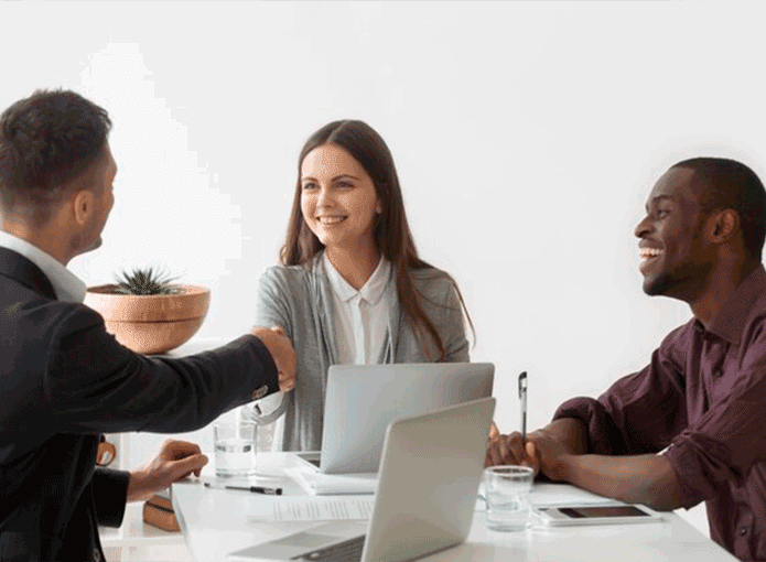 Um grupo de pessoas sentadas ao redor de uma mesa apertando as mãos