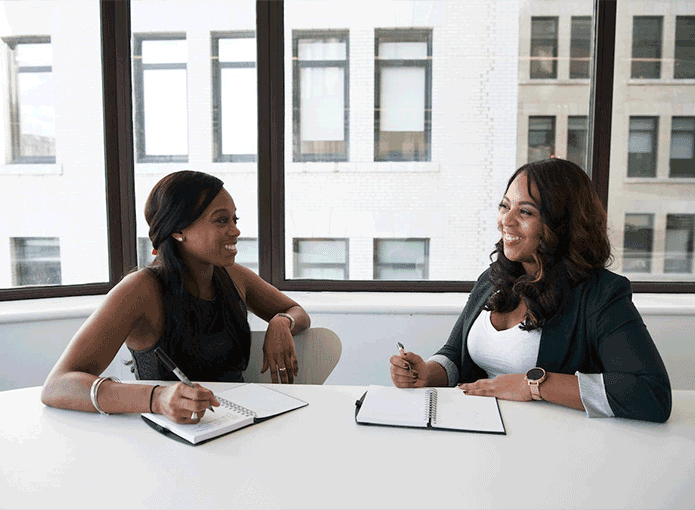 Duas mulheres sentadas à mesa com cadernos