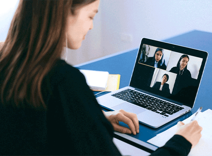 Uma mulher sentada em uma mesa em frente a um notebook