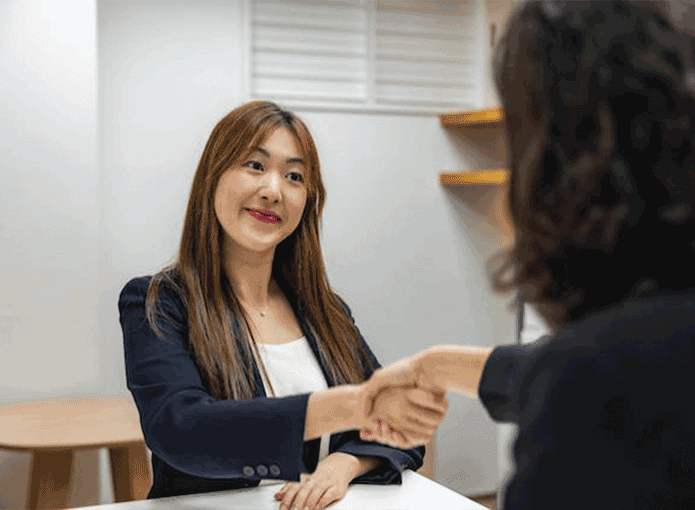 Uma mulher apertando a mão de outra mulher em uma mesa