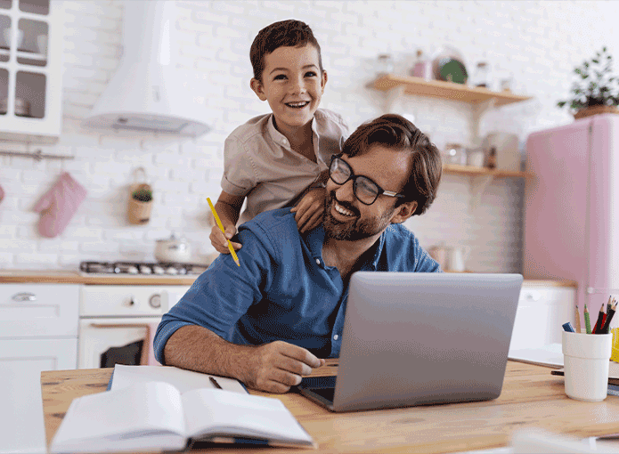 Um homem segurando uma criança enquanto olha para um laptop