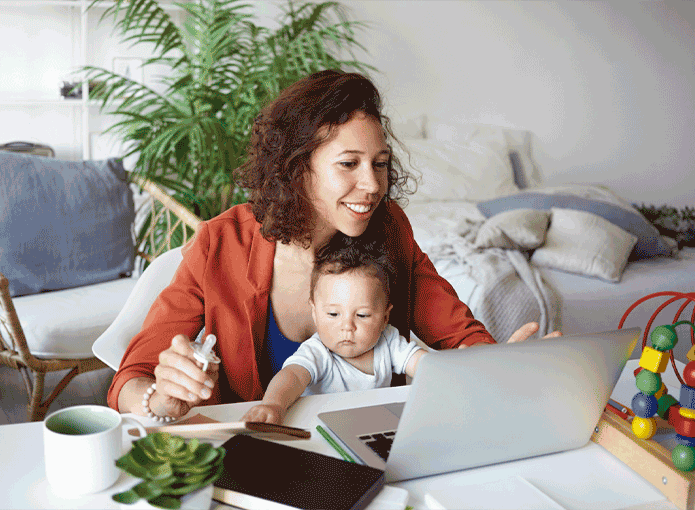 Uma mulher sentada à mesa com uma criança na frente de um laptop