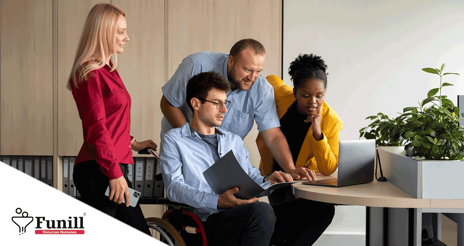 A group of people standing around a table with a laptop