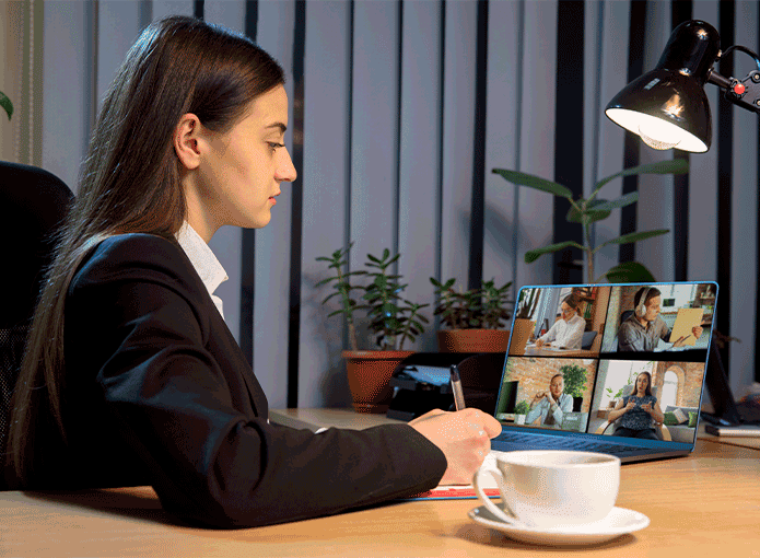 Uma mulher sentada em uma mesa em frente a um laptop