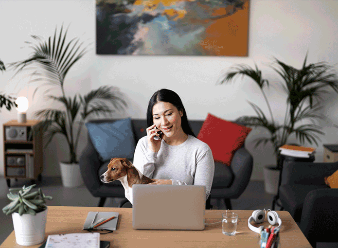 Uma mulher sentada à mesa com um cachorro no colo